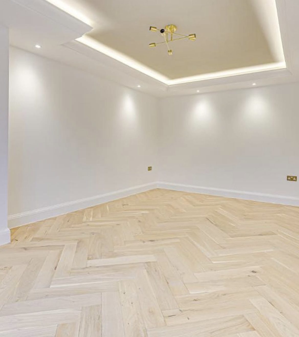 Room with herringbone oak flooring and feature ceiling lighting