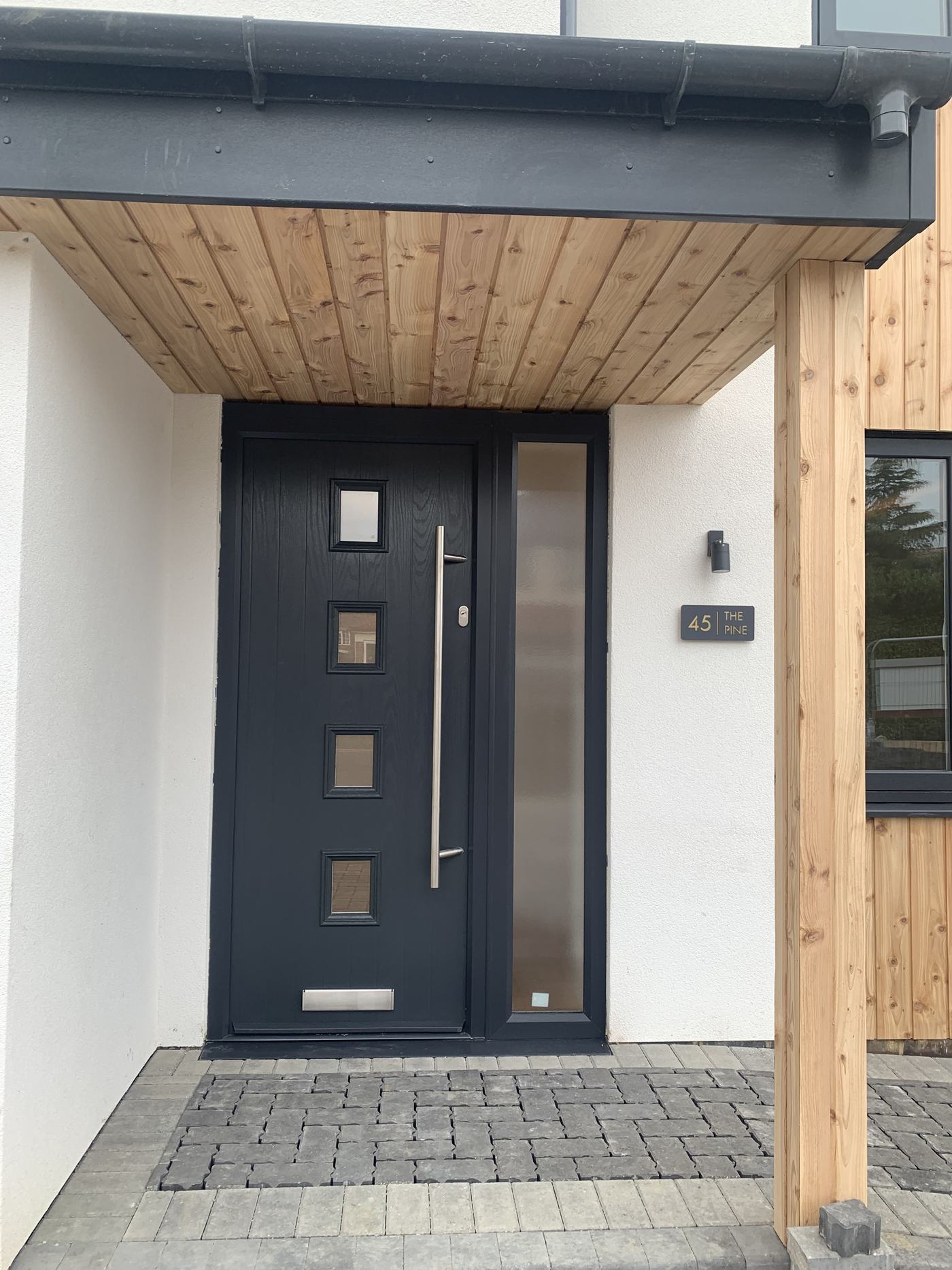 Modern black front door with timber canopy porch