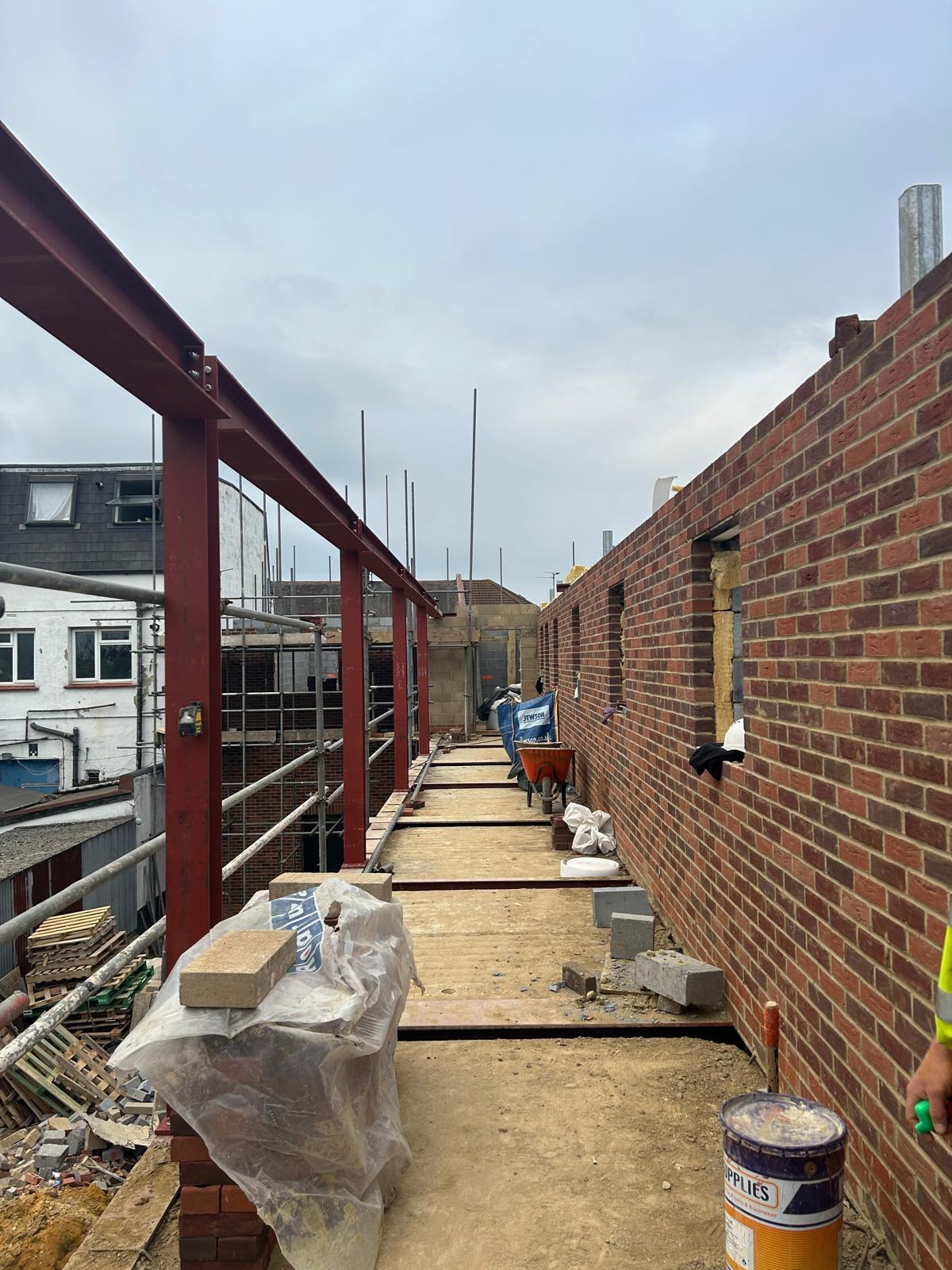 Steel frame walkway alongside a brick wall on site